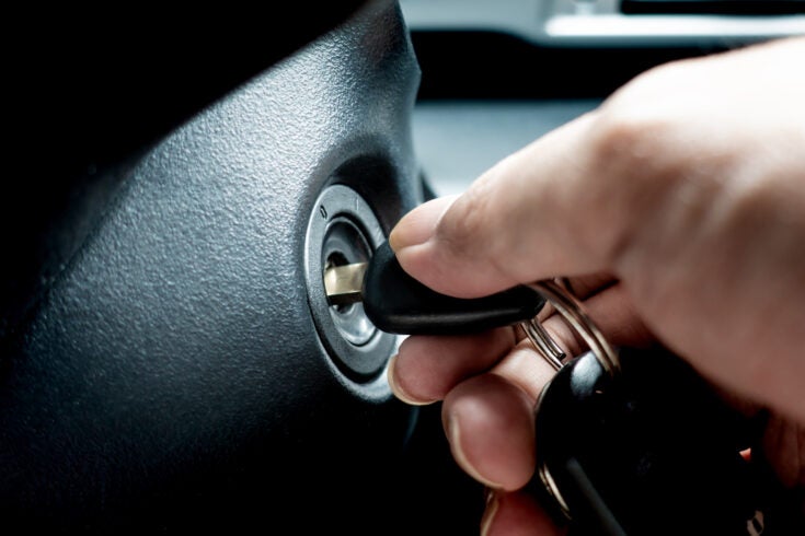 a hand turning the key in a car