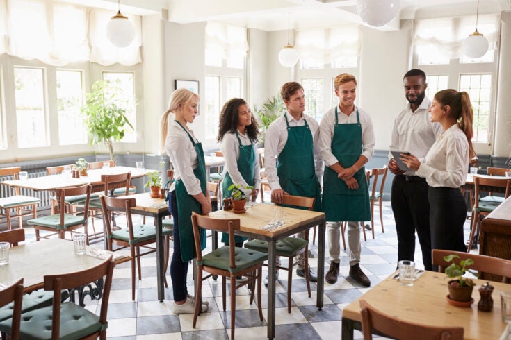 a group of restaurant workers in a stand up meeting