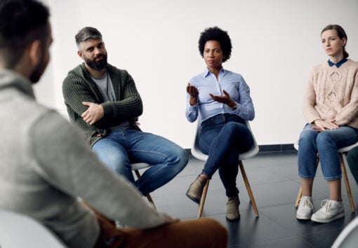 Social worker talking to participants of group therapy at community center.