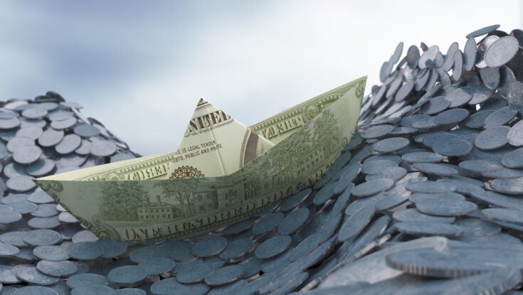 a stylized photo of a boat made of money navigating waves of coins