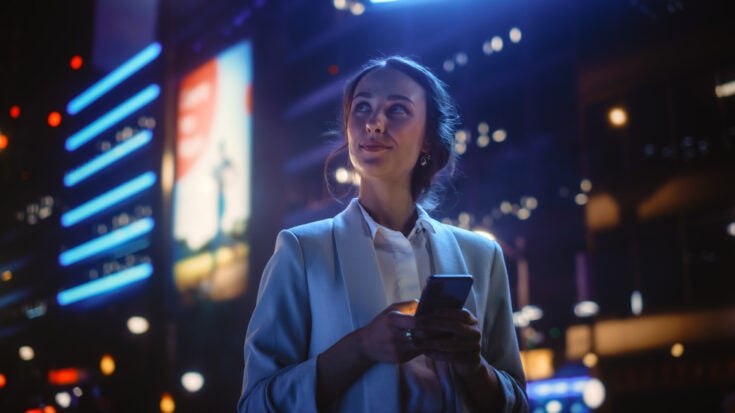 a woman smiling as she uses her android device
