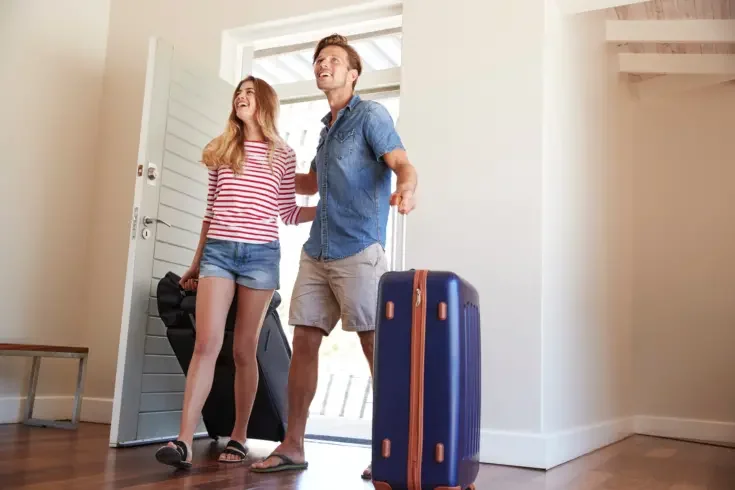a vacationing couple happily arriving at their rental