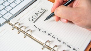 Close-up of a businessman's hand writing goals and list in the diary