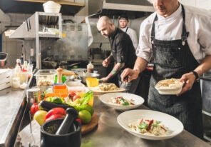 a group of chefs preparing food with fresh ingredients in a kitchen