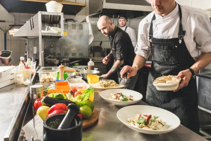 a group of chefs preparing food with fresh ingredients in a kitchen
