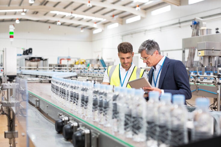 a Supervisor and manager watching plastic bottles on conveyor belt
