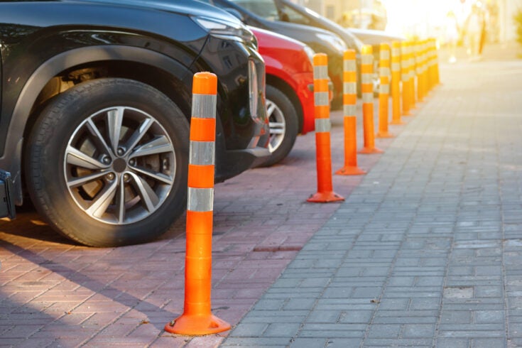cars lined up and parked behind orange cones