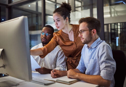 A team member showing two other team members information on a computer