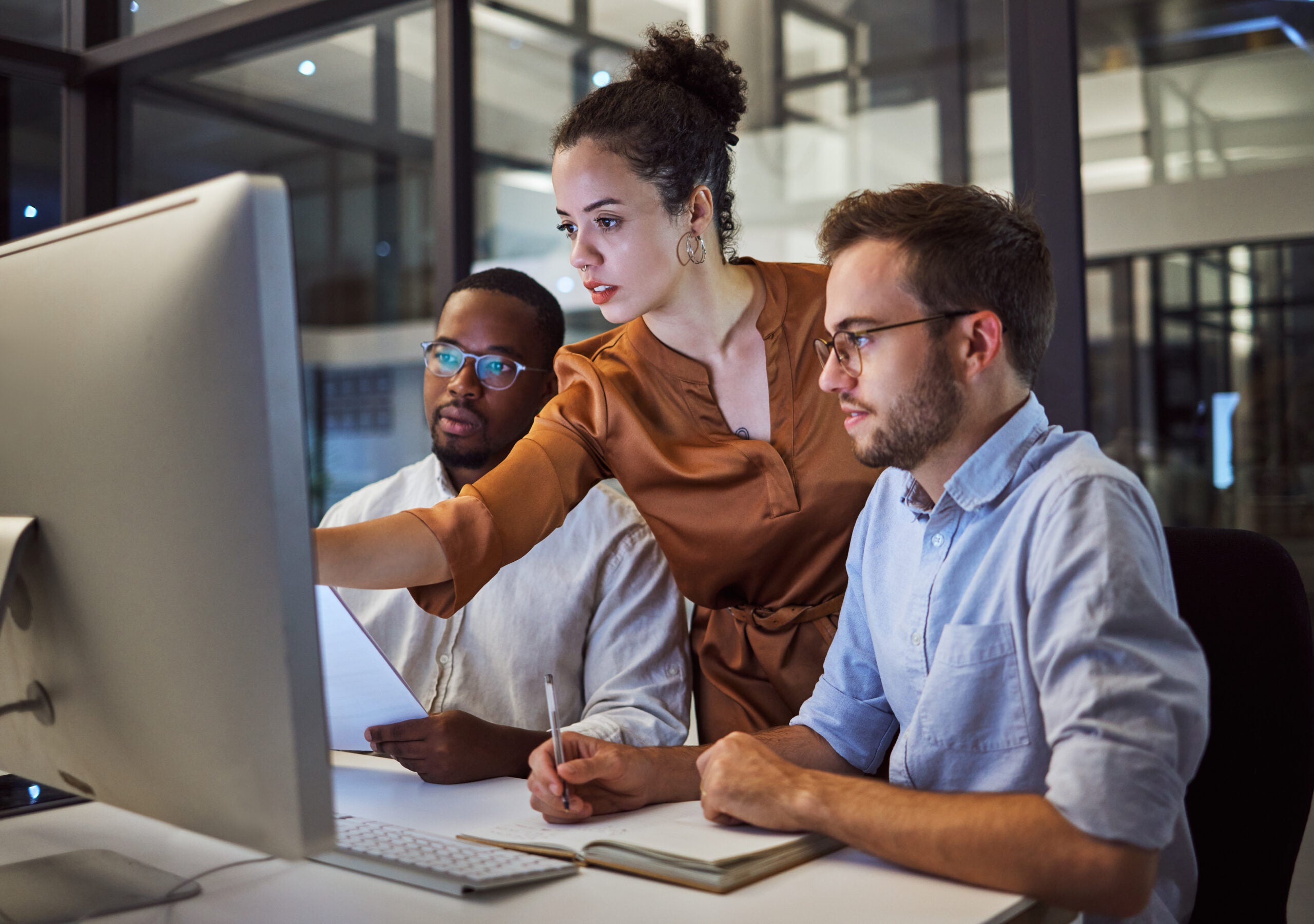 A team member showing two other team members information on a computer