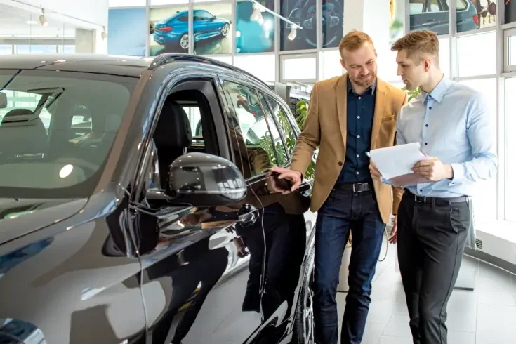 a car salesperson showing a customer a vehicle