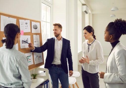 a team member pointing to a graph as other team members look on