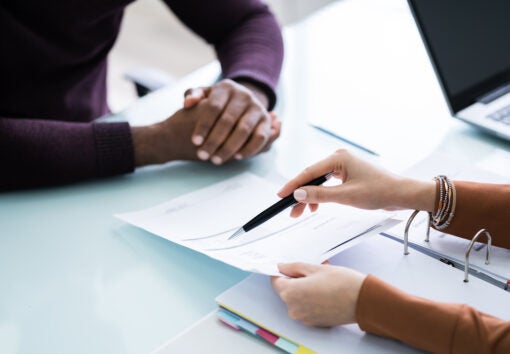 Young Financial Advisor Discussing Invoice With Her Client At Workplace