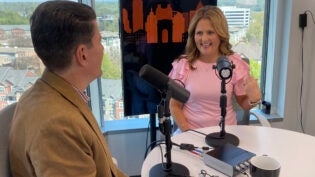 Young attractive woman in pink talking in studio on podcast