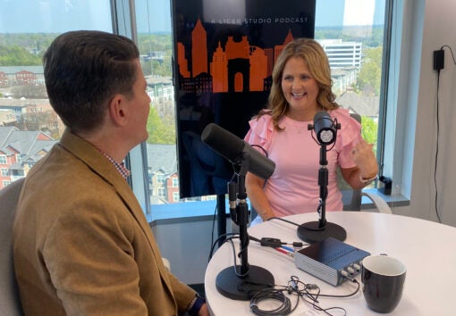 Young attractive woman in pink talking in studio on podcast