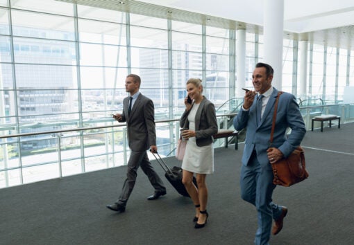 Business people talking on mobile phone while walking in the corridor