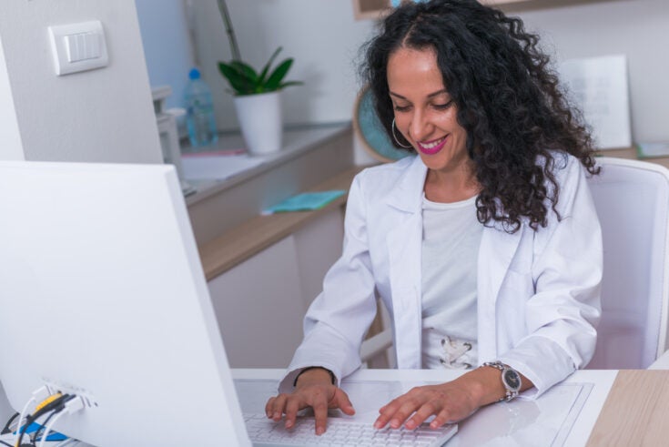 Portrait of a medical worker typing a medical report on her computer in the lobby.