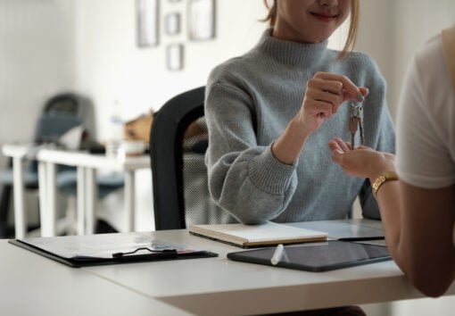 real estate agent holding house key to his client after signing contract agreement in office,concept for real estate, moving home or renting property.
