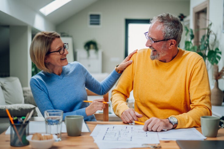 Happy senior couple enjoying their time at home and examining housing plans while relocating into a new house. Elderly couple moving into a new house. Investing in the new property, mortgage.