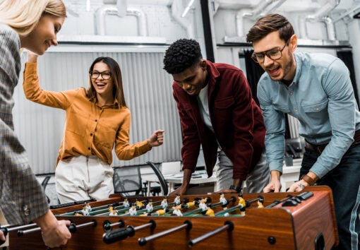 multicultural business colleagues playing table football together in office