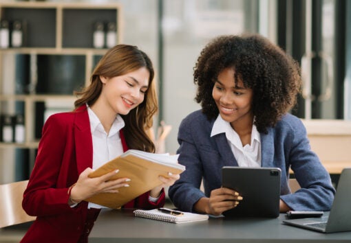 Two businesswoman discuss investment project working and planning strategy with tablet laptop computer in modern office.