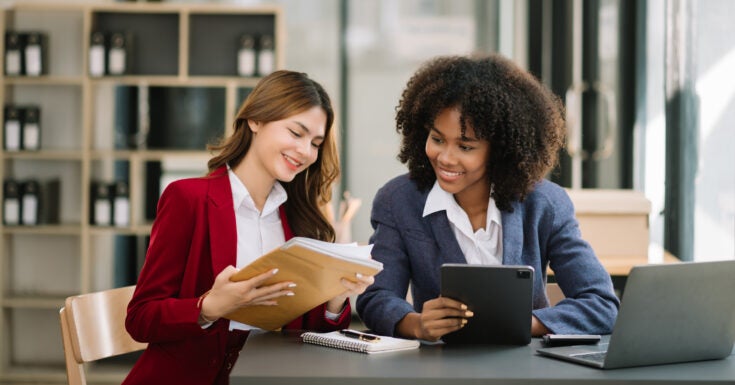 Two businesswoman discuss investment project working and planning strategy with tablet laptop computer in modern office.
