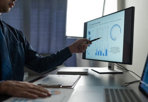 Businessman analyzing financial data statistics on pc computer pointing at screen with graph Chart showing company growth using easy accounting software to plan. Management for start-up business.