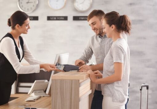 Man and woman checking in at hotel desk