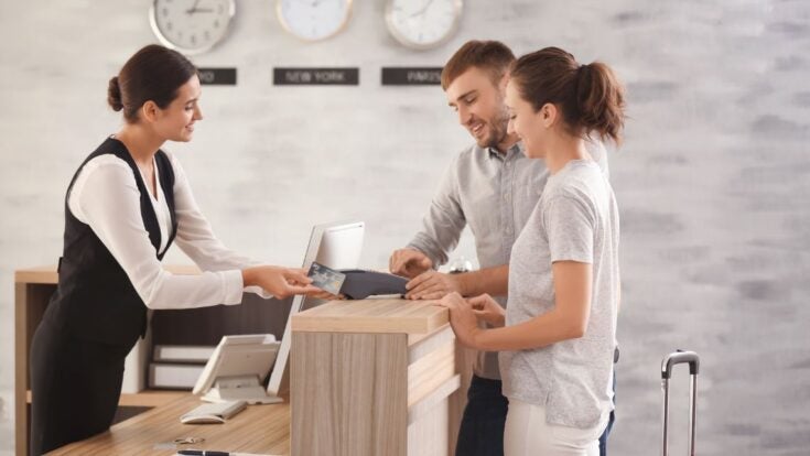 Man and woman checking in at hotel desk