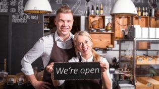 Coffee shop owners showing open sign