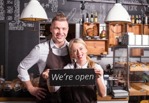 Coffee shop owners showing open sign