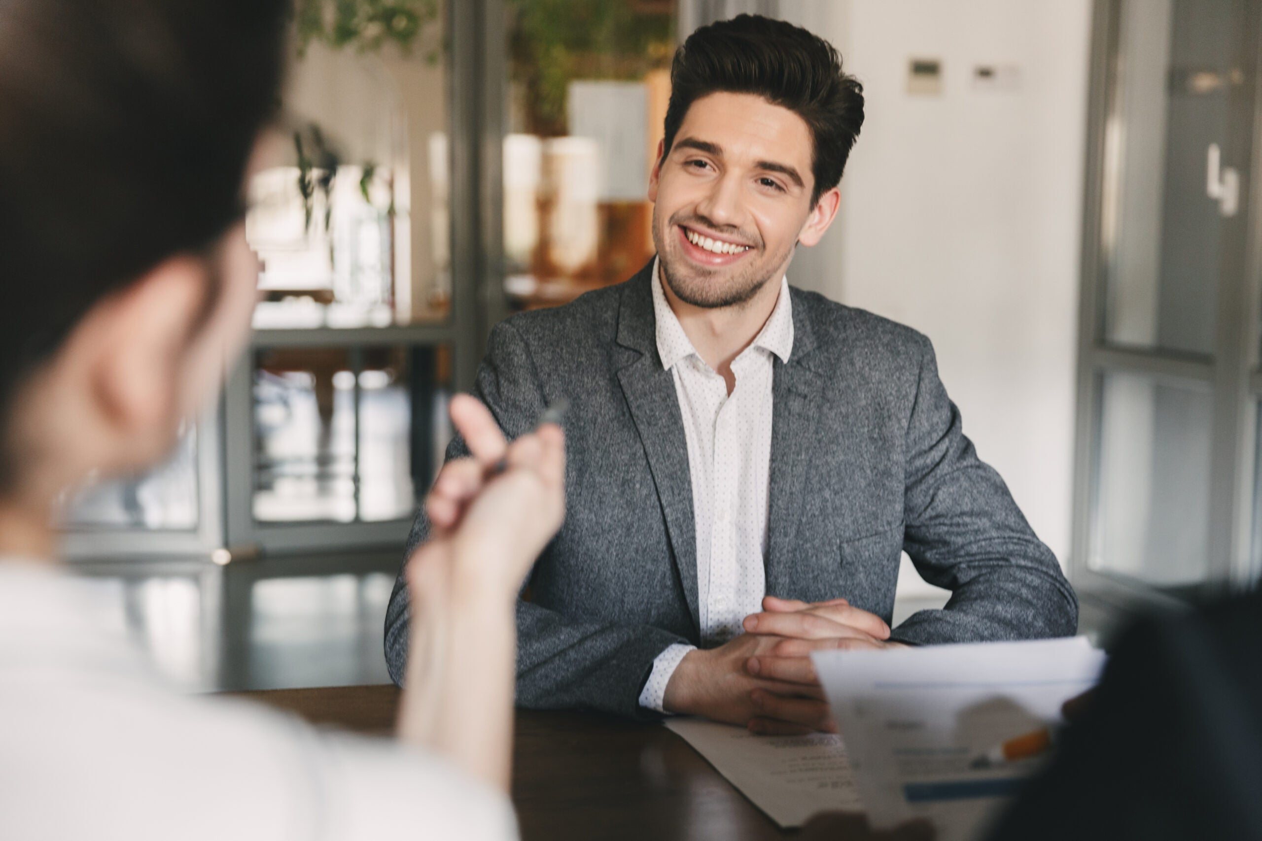 Business, career and placement concept - smiling caucasian man 30s negotiating with committee of businesslike people during job interview in office