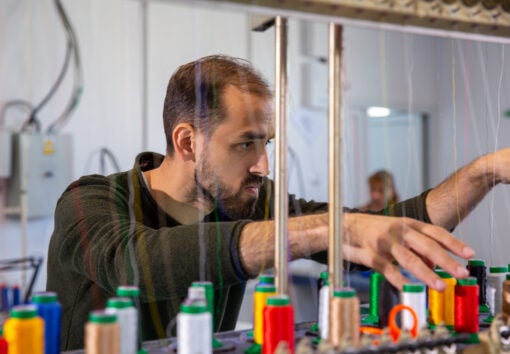 Worker at the textile factory that arranges the spools of yarn. Industrial machines