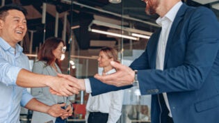 Men are shaking their hands in modern office