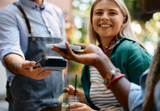Close up of female cafe guest using smart phone while making payment.