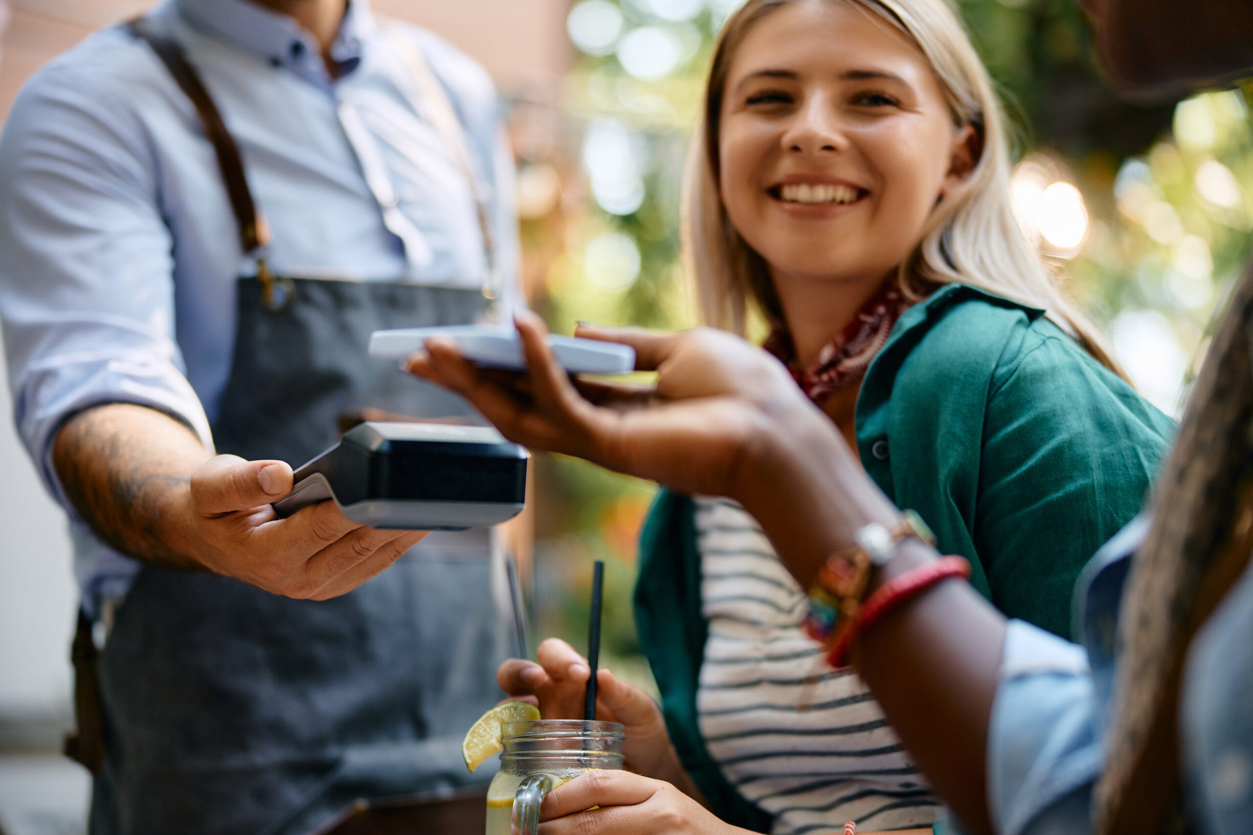 Close up of female cafe guest using smart phone while making payment.