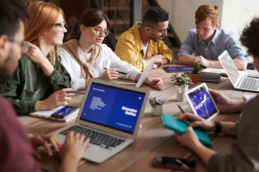 Workers sitting around table with laptops