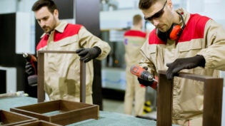 Two young workers assembling furniture in the factory