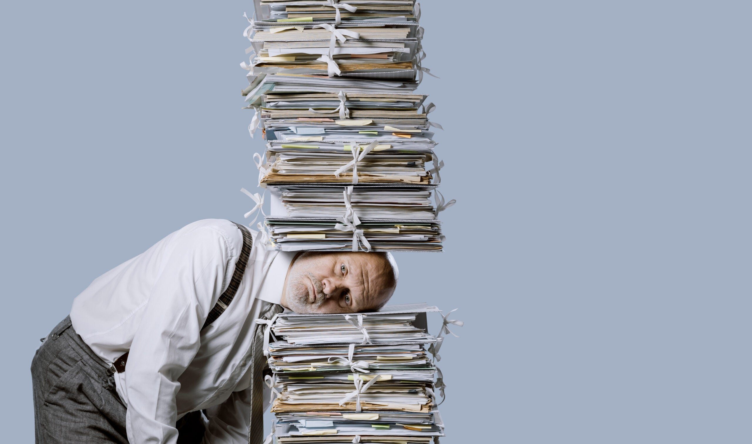 Stressed businessman under a pile of paperwork