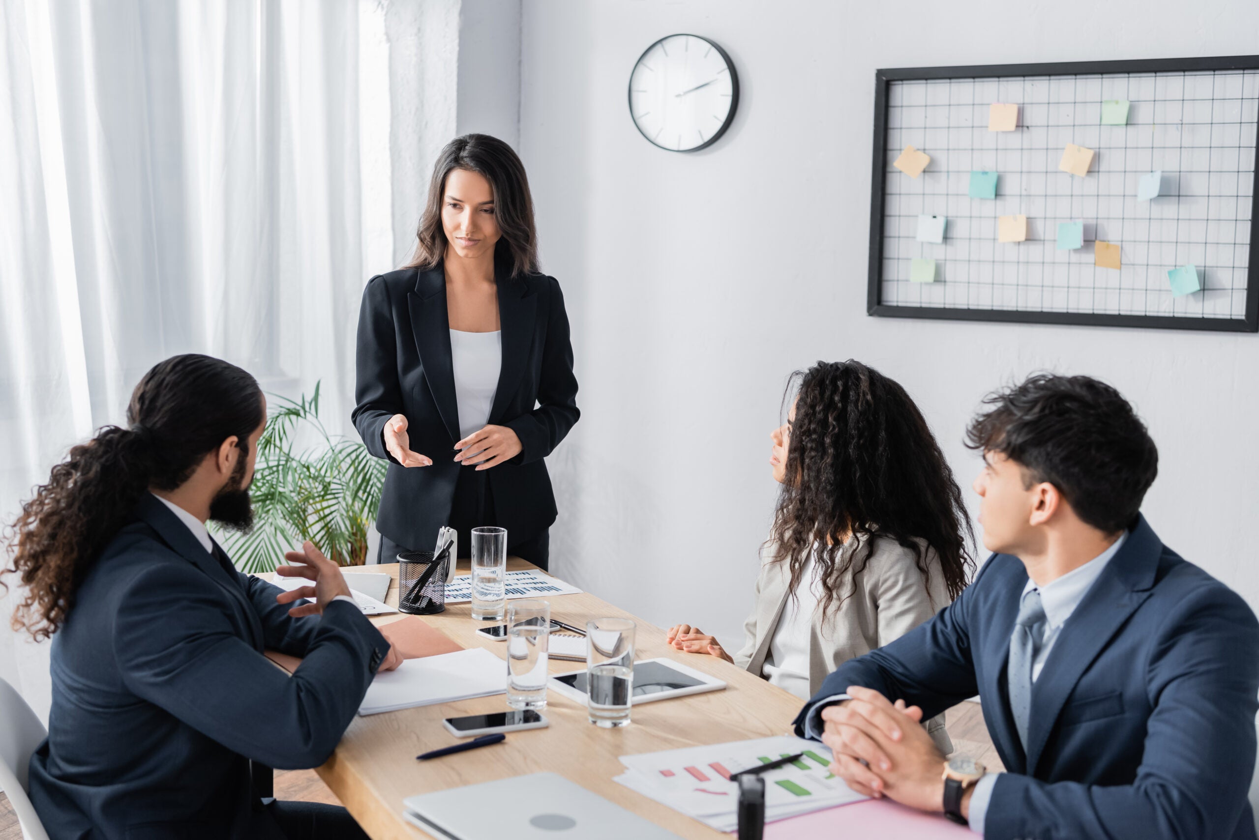 businesswoman standing and pointing with hand at co-worker during business meeting in office