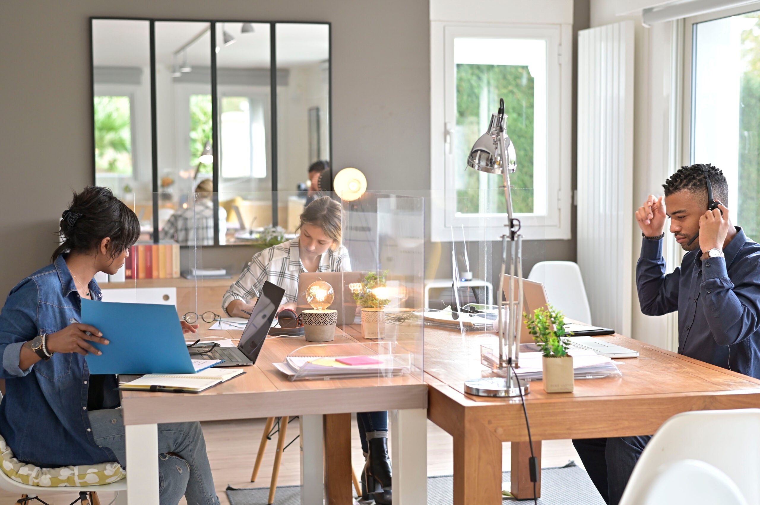 View of co-workers in open space office protected by plexiglas