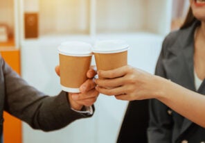 Two business people standing and holding a coffee cup in modern office