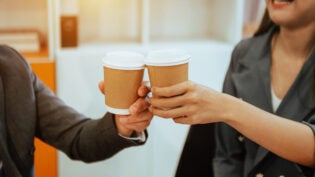 Two business people standing and holding a coffee cup in modern office