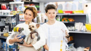 Mom and son with goods for pet, dog food, and related products at pet shop