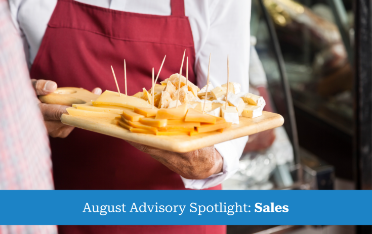 salesman holding cutting board with assorted cheese in store