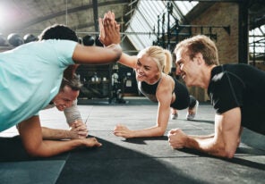 women high fiving together while planking at the gym