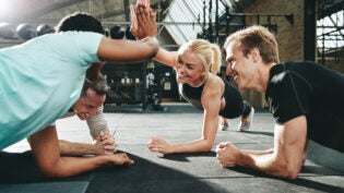 women high fiving together while planking at the gym