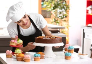 Young female confectioner with sweets in kitchen