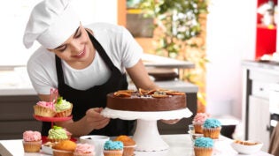 Young female confectioner with sweets in kitchen