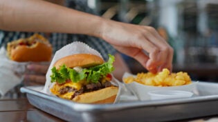 Woman eating burger in fast food restaurant