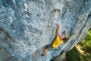 top view of man rock climber in yellow t-shirt, climbing on a cliff